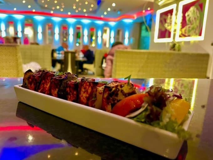 Paneer tikka on a long platter, served in Nibana's neon-lit dining room
